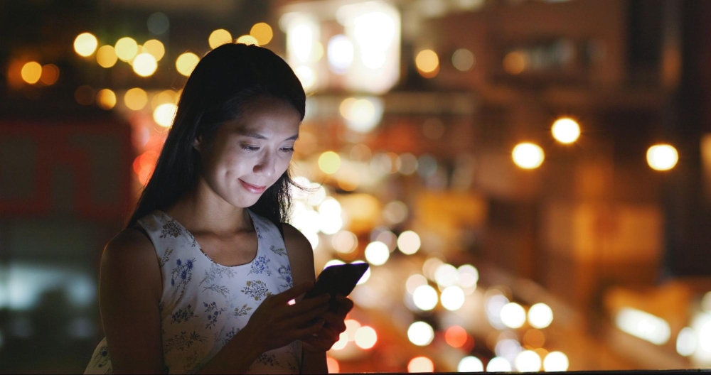 A woman a night using her mobile phone.